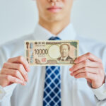 現金（1万円札）を持つ男性